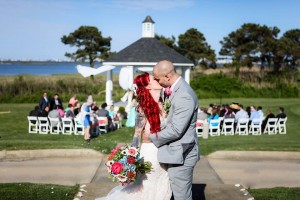 bride and groom kissing with gazebo and guests behind them
