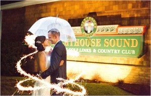 bride and groom standing outside of Lighthouse Sound with umbrella