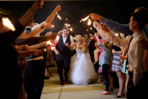 bride and groom smiling walking through guests holding sparklers