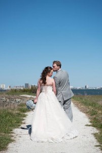 bride and groom posing with ocean city skyline behind them