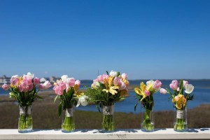 wedding bouquets lined up in glass jars with bay behind them