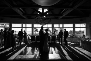 black and white photo of bride and groom dancing with guests watching