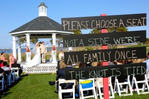 bride and groom standing in gazebo with sign to choose a seat